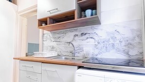 A kitchen with white cabinets, a marble backsplash, a wooden countertop, and a built-in dishwasher. - Beautiful 1BR Near Danube Praterstern (Vienna)