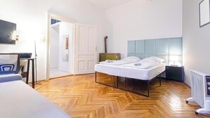 A bedroom with a bed, a desk, a chair, a ceiling fan, and a radiator. - Beautiful 1BR Near Danube Praterstern (Vienna)