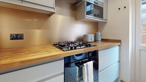 Una cucina con piano di lavoro in legno, fornello a gas, forno integrato e lavatrice.