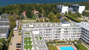 A multi-story hotel with a rooftop pool, surrounded by greenery and a view of the sea. - Seaside Apartment | 300 m to the Beach, Pool, Parking (Kołobrzeg)