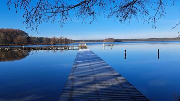 A wooden pier extending into calm water with a forested shoreline in the background.