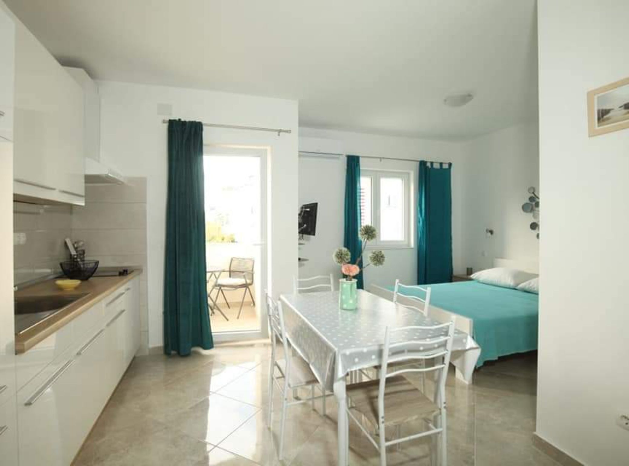 A compact room with a kitchenette, a dining area, and a bed.