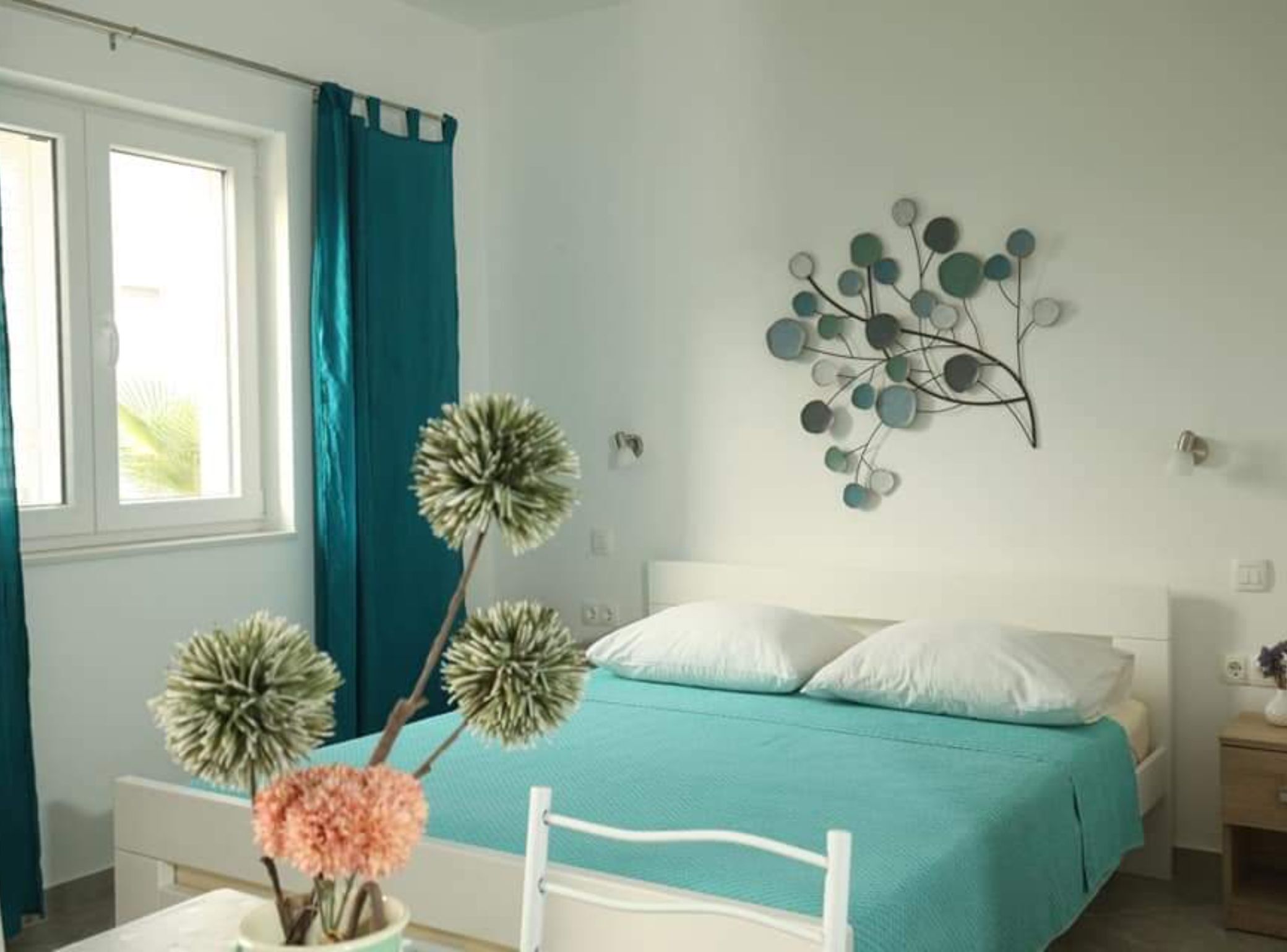 A bedroom with a bed, a wall-mounted decoration, and a window with curtains.