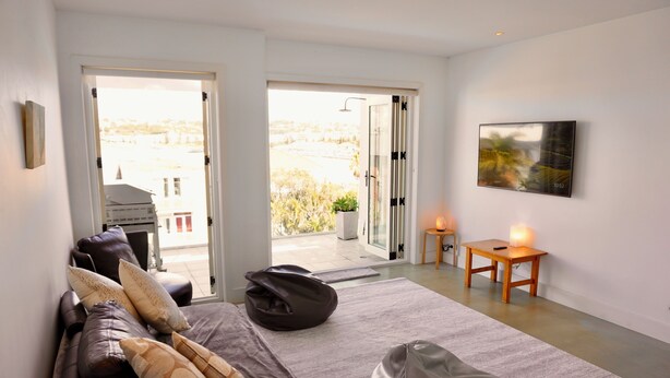 A modern living room with a sofa, a bean bag, a small table with a candle, and a painting on the wall. - Sunny Side Up North Bondi (North Bondi)