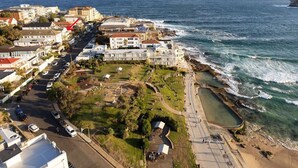 An aerial view of a coastal town with a marina, a promenade, and buildings along the shore. - Sunny Side Up North Bondi (North Bondi)
