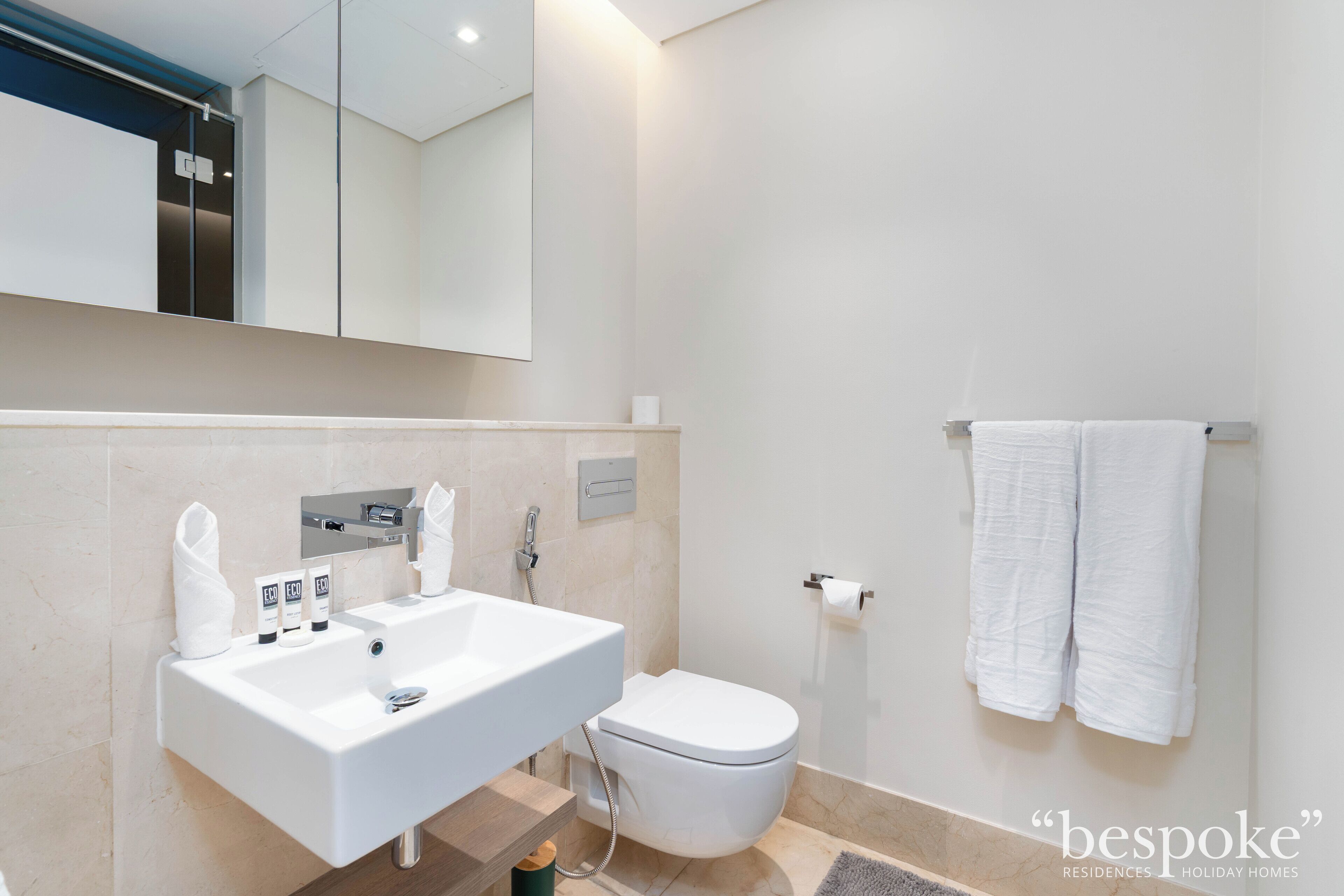 Een moderne badkamer met een groot wastafel, toilet en handdoekrek.
