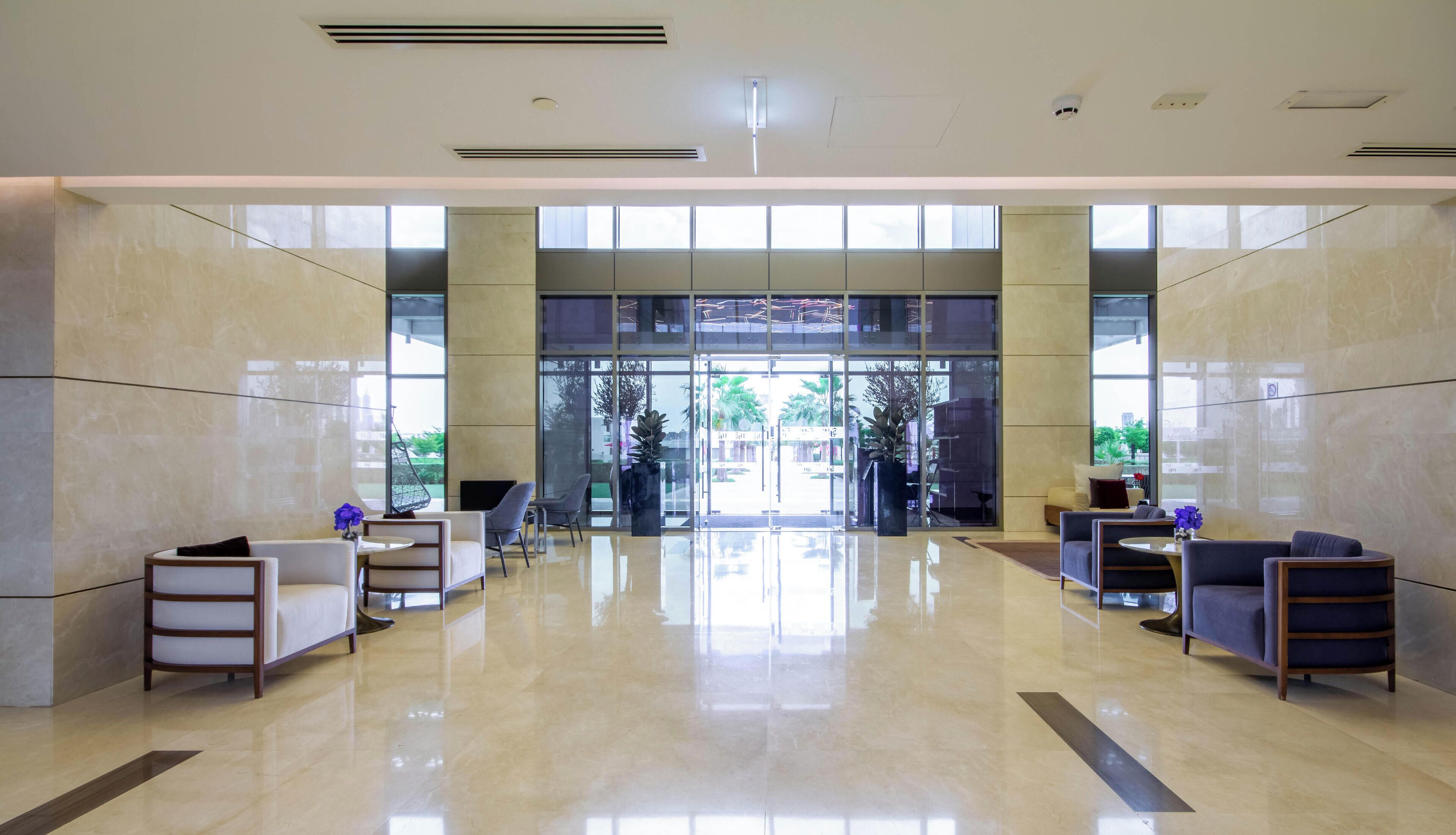 A spacious lobby with a polished marble floor, large windows, and modern seating arrangements.