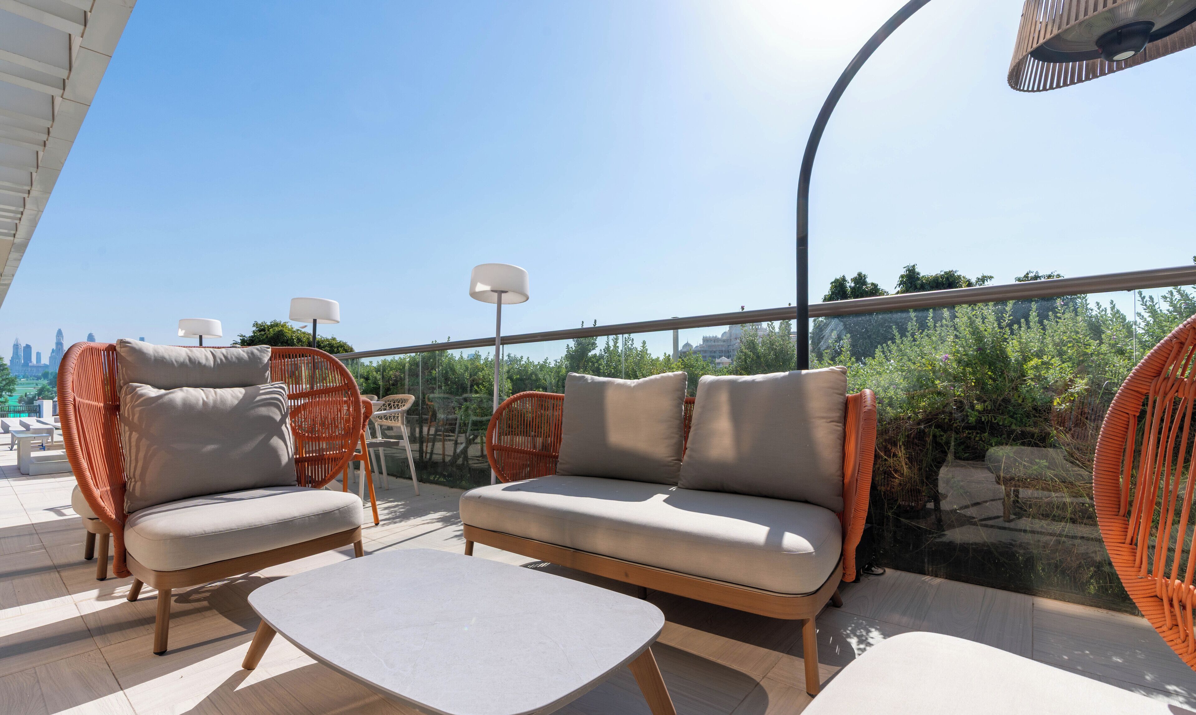 A rooftop terrace with wicker furniture, a sofa, and a table.