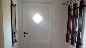 Una porta blanca amb un petit finestret, un pom i un interruptor de llum. Al costat dret, hi ha una prestatgeria metàl·lica amb claus.