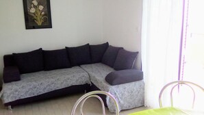 Un saló amb un sofà gris, un quadre al mur i una finestra amb cortines.