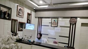 Un mostrador de recepción con un monitor de computadora, cuadros en la pared y un reloj.