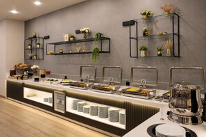 Un buffet avec plusieurs points de service, des étagères en verre ornées d’objets décoratifs et une grande variété de plats proposés.