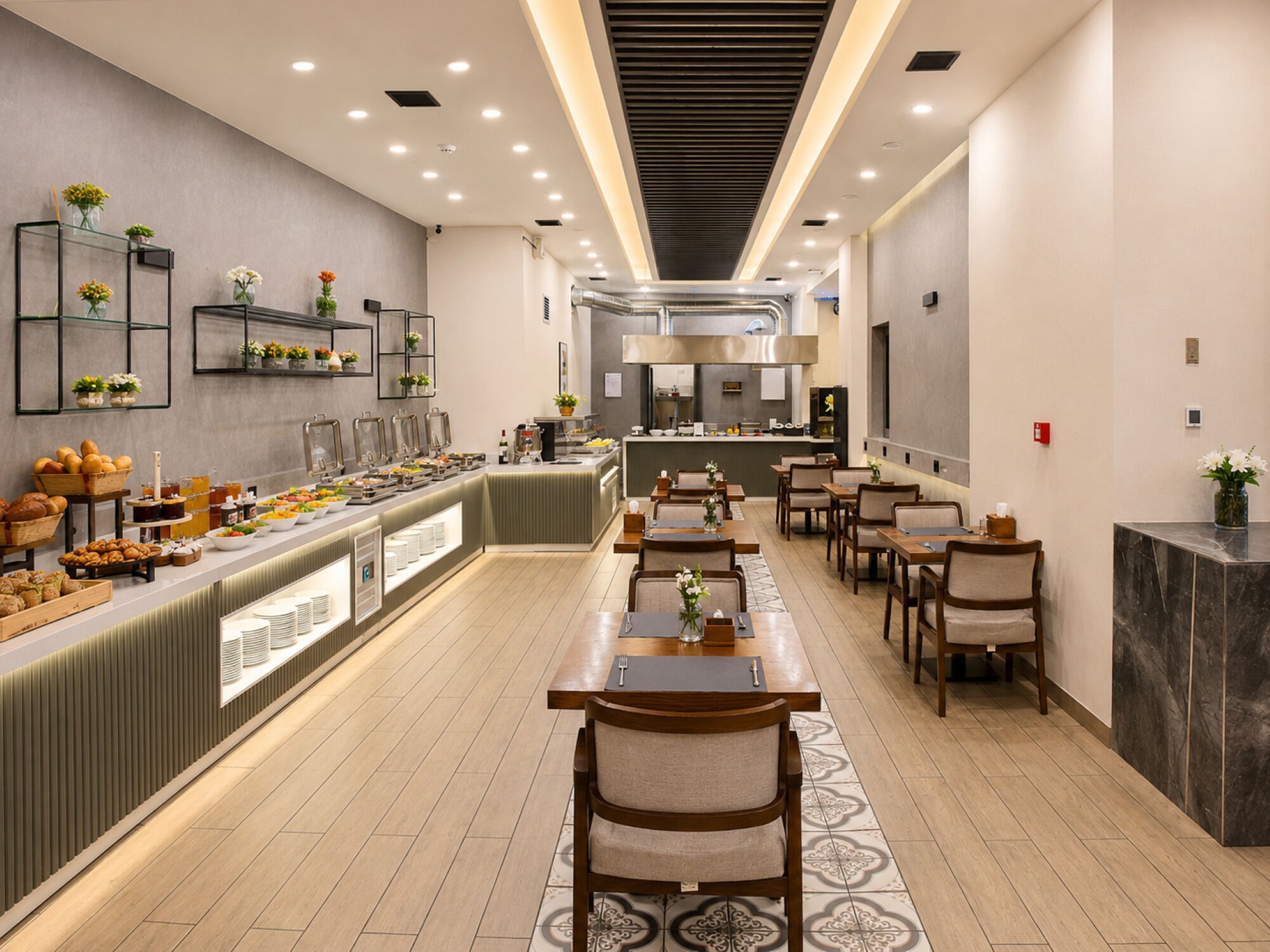 A buffet area with a variety of food items, a long counter with seating, and a kitchen in the background.