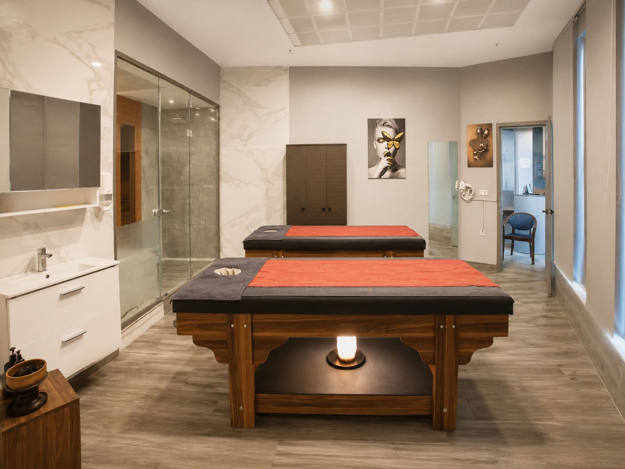 Quarto moderno com mesa de massagem, armário de madeira e box de vidro.