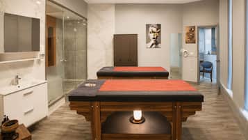 Quarto moderno com mesa de massagem, armário de madeira e box de vidro.