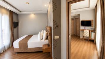 A hotel room with a bed, a desk, a television, and a wardrobe.