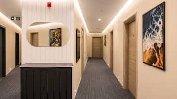 A hotel hallway with a reception desk, a fire alarm, and artwork on the walls.