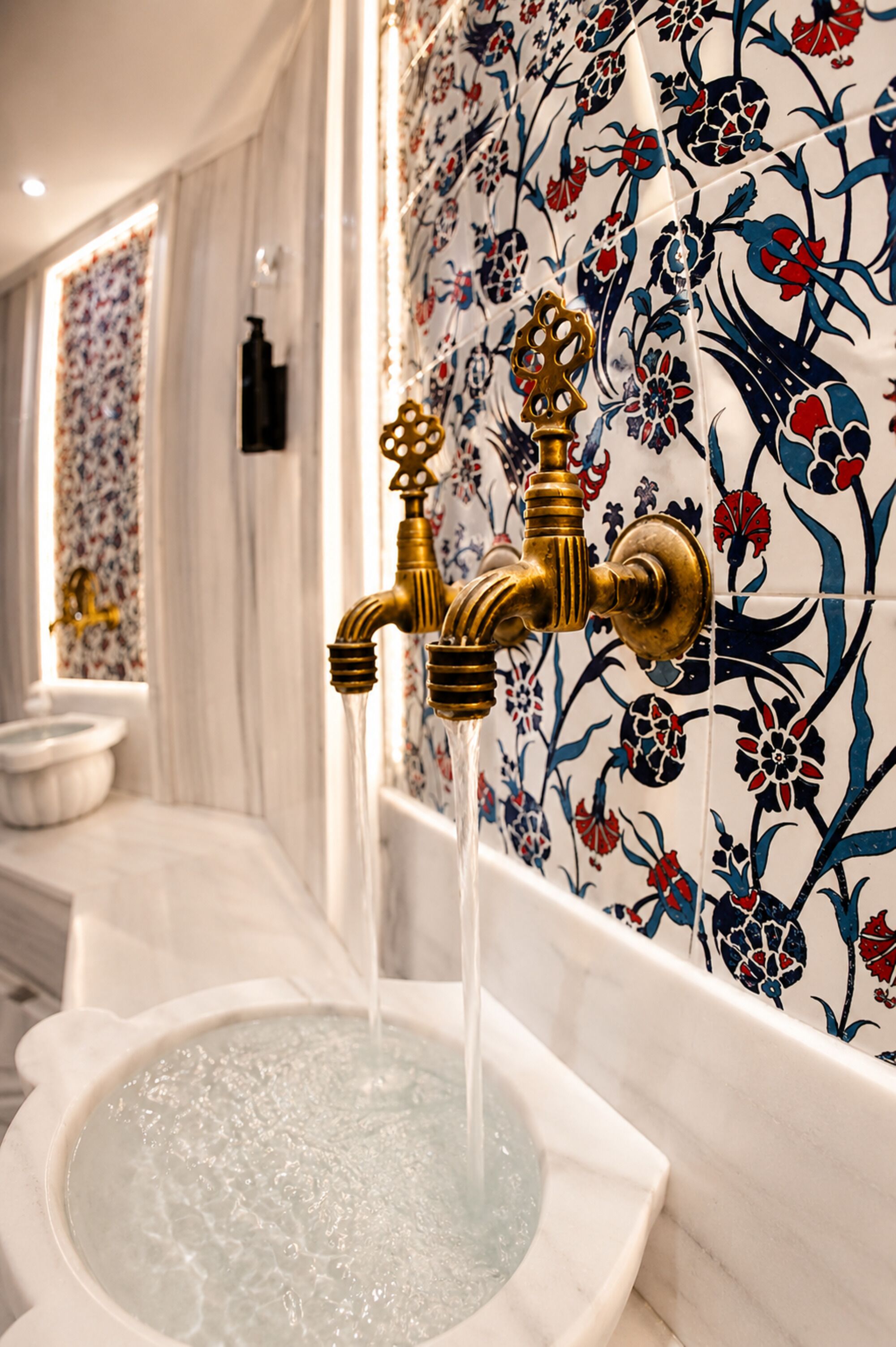 Un baño con bañera, grifo dorado y papel tapiz con estampado floral.