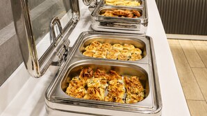 A buffet line with various food items in stainless steel chafing dishes, a coffee machine, and a wine bottle on the counter. - Elite World Inn Istanbul Mahmutbey (Istanbul)