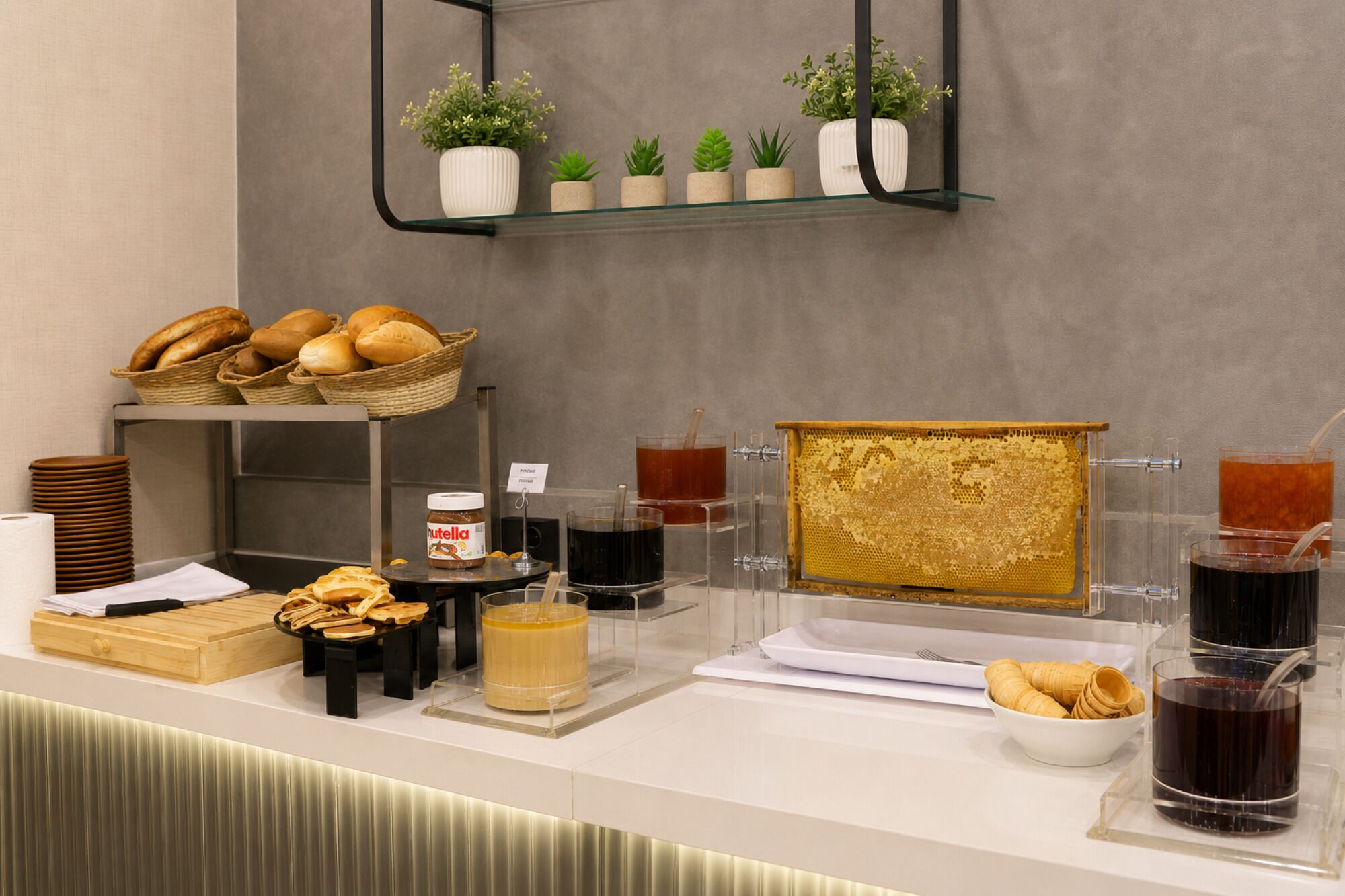 A breakfast buffet with bread, pastries, and condiments.