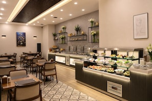 A modern restaurant with a buffet counter, dining tables, and chairs.