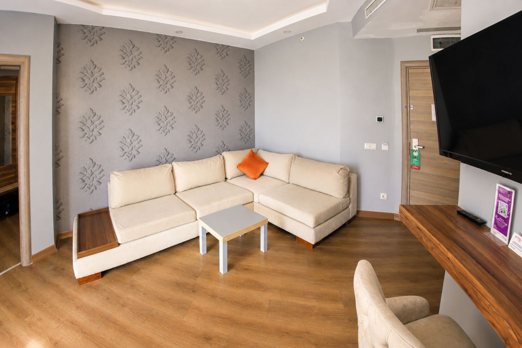 A modern living room with a sectional sofa, a coffee table, and a flat-screen TV.