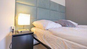 Un lit bien fait, avec du linge de lit blanc et un oreiller moelleux, une table de chevet avec une lampe et une tête de lit moderne.