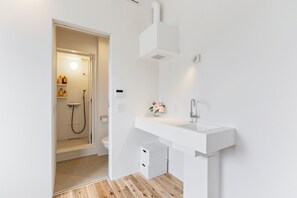 Une salle de bain moderne avec un lavabo, une douche et des toilettes, le tout de couleur blanche.
