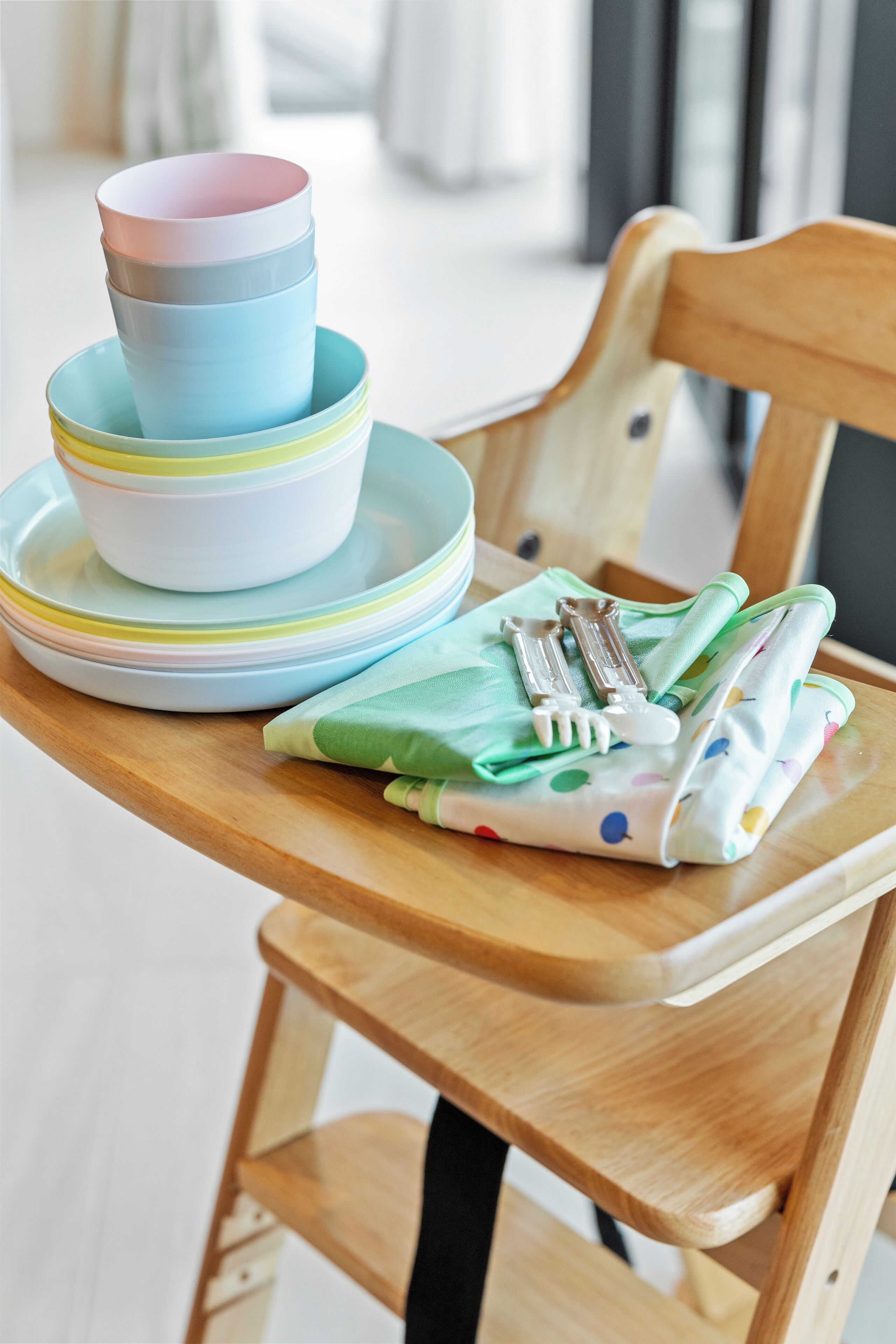 A wooden chair with a green and white polka dot napkin holder containing utensils.