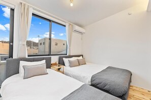 Une chambre d’hôtel moderne avec deux lits, une grande fenêtre avec des rideaux et un appareil de climatisation.