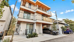 Ein modernes, mehrgeschossiges Wohngebäude mit Garage, einem schwarzen Auto davor und einem kleinen Garten.