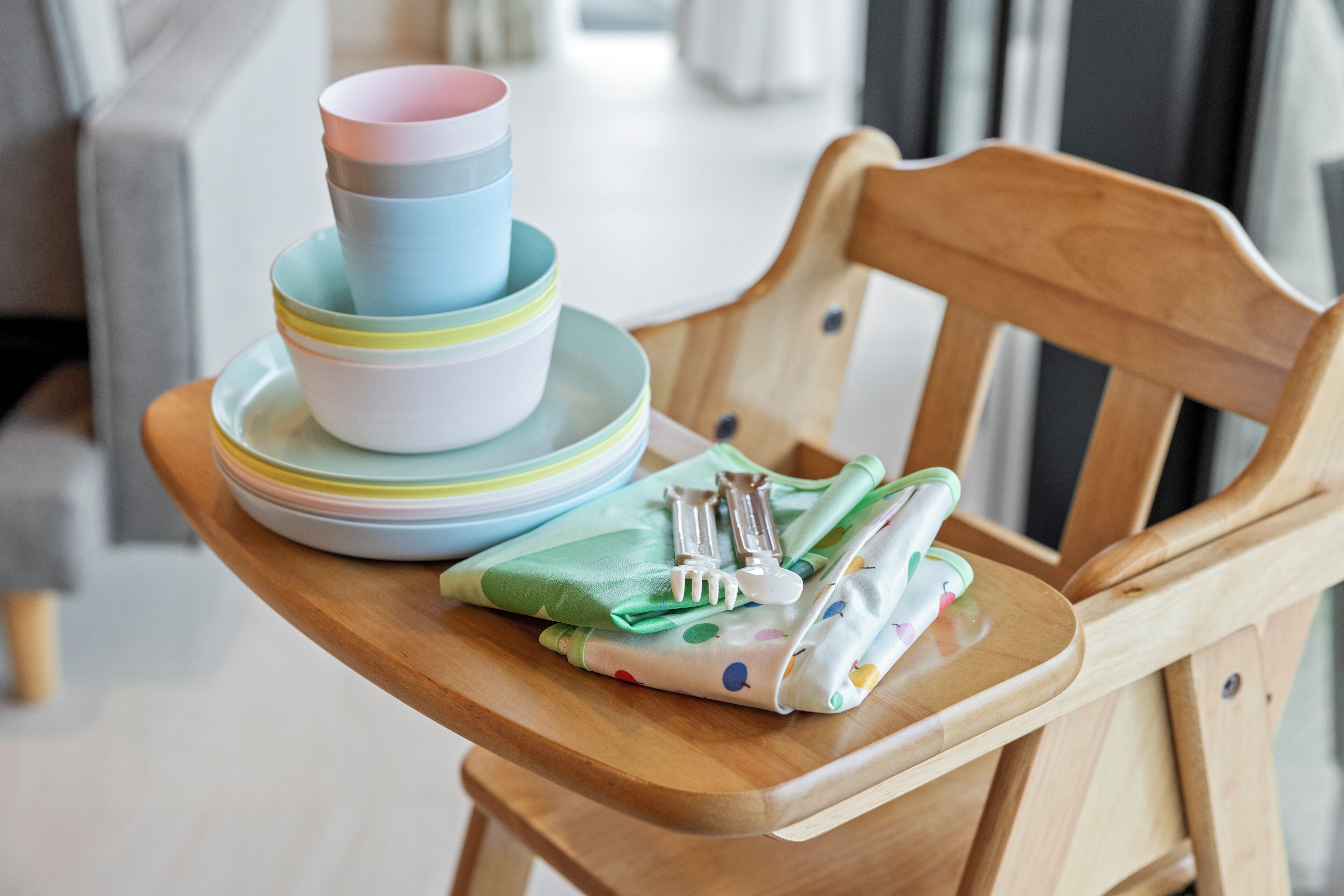 A wooden chair with a stack of colorful plates and a green napkin with a fork and spoon on it.