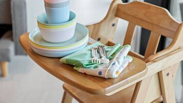 A wooden chair with a stack of colorful plates and a green napkin with a fork and spoon on it.