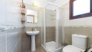 A bathroom with a glass-enclosed shower, a pedestal sink, and a toilet. - Nissi Apartment #101 (Ayia Napa)