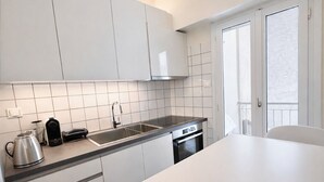 Una cocina moderna con armarios blancos, un lavamanos de acero inoxidable y un horno empotrado.