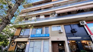 Un edificio de varios pisos con diversos comercios en la planta baja, como una panadería, un café y una barbería.
