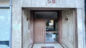 Entrada de un edificio con una puerta de madera, el número 58, y una pequeña zona empavedada al frente.