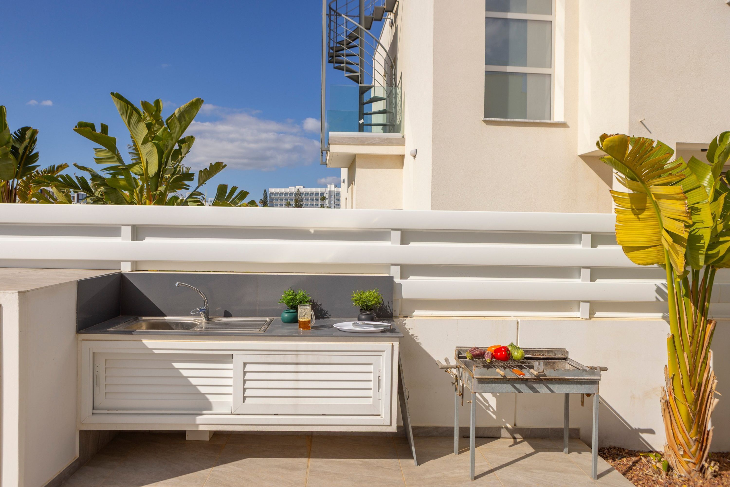 Un espace cuisine extérieur comprenant un évier, une petite table et un barbecue.