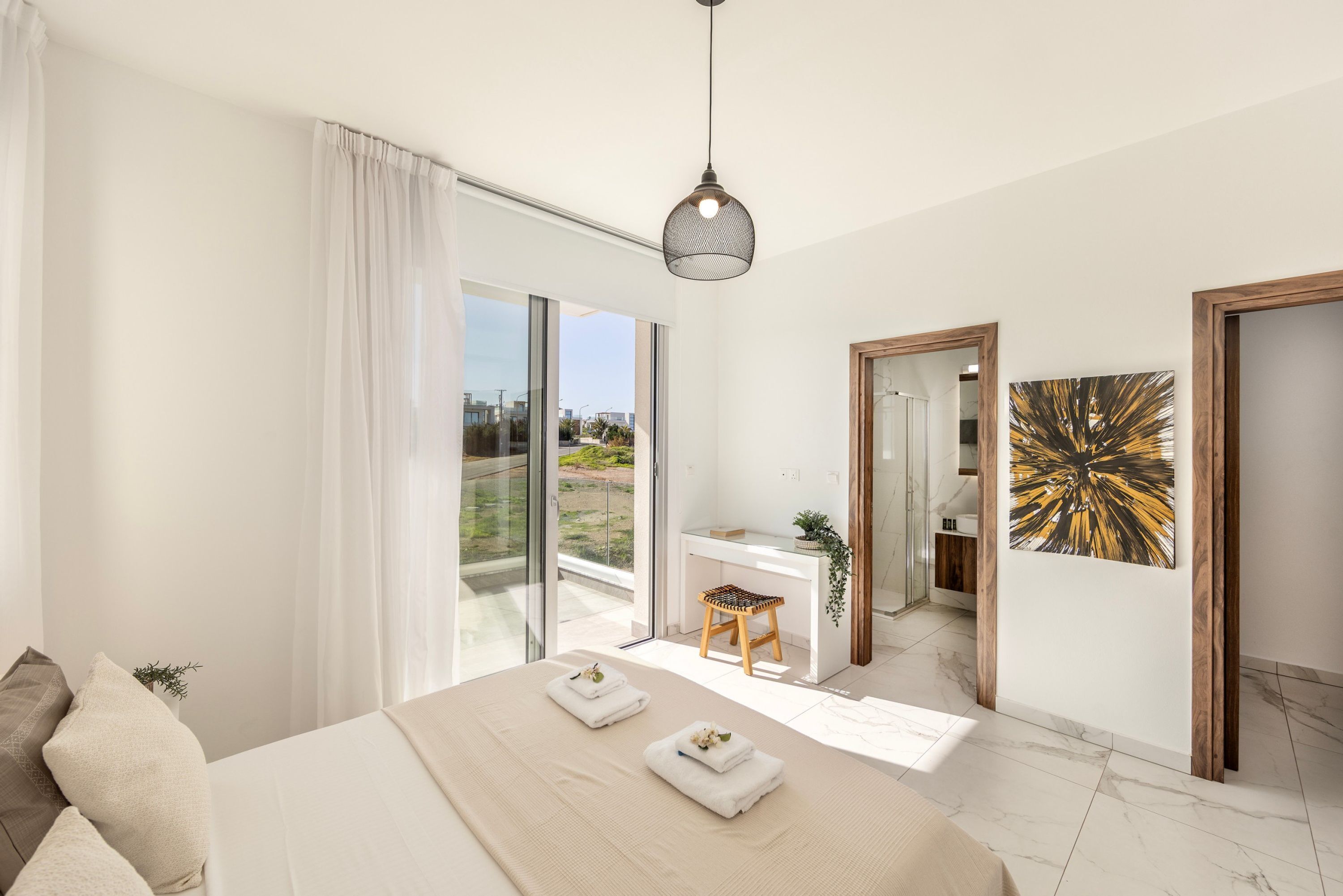A modern bedroom with a large bed, a desk, and a view of the city.