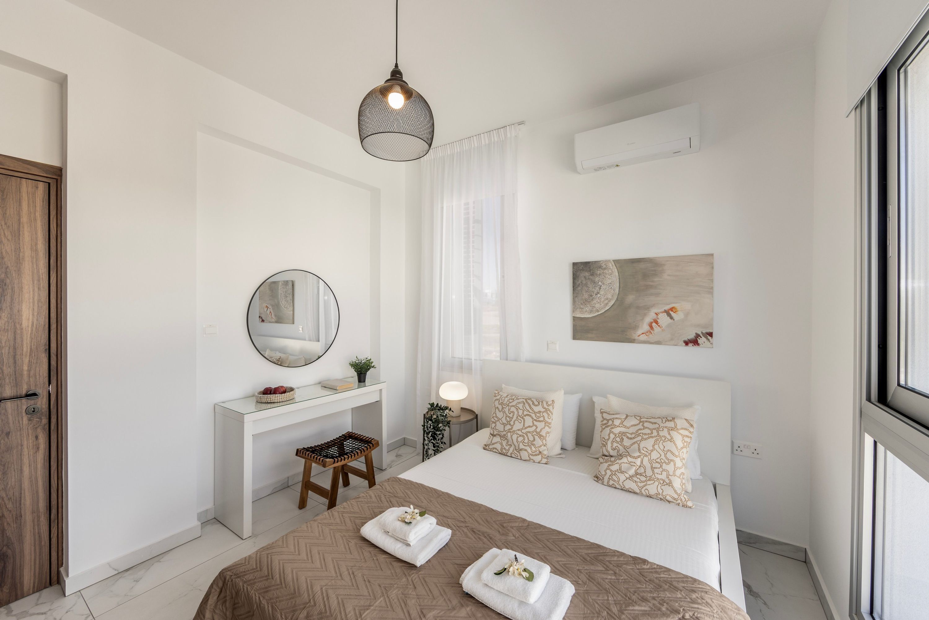 A modern bedroom with a bed, bedside table, mirror, and artwork.