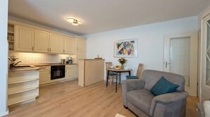 A compact living space with a kitchenette, dining area, and a sofa.