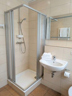 A modern bathroom with a glass-enclosed shower, a white sink, and a mirror above the sink. - FeWo Jette in Warnemünde (Rostock)