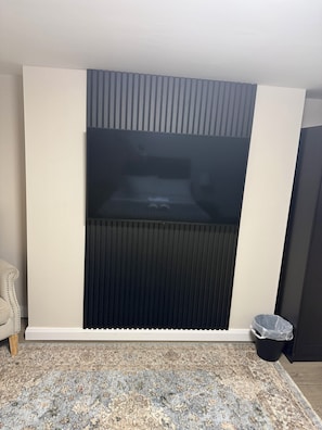 Ein Zimmer mit einer großen, dunkel gefärbten Wandpaneele, einer weißen Fußleiste, einem gemusterten Teppich und einer kleinen Mülleimer.