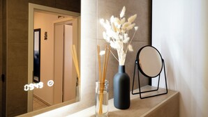 Ein Spiegel, eine Vase mit Schilf und ein Ablageflächenelement auf einer Theke.