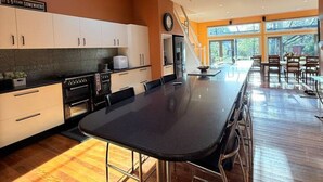 A modern kitchen with a skylight, a dining area with a long table, and a view of the outdoors. - Brecon Cottage | Serene 3BR Blue Mountains Escape (Leura)