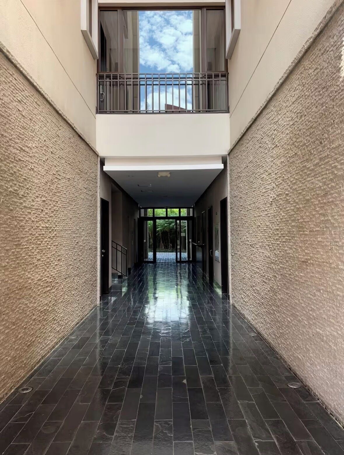 Un pasillo de diseño moderno, con piso negro pulido y paredes beige con textura.