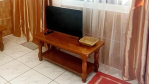 A room with a wooden TV stand, a remote control, and a small tray. - Apartment Oasis Costa Calma (Costa Calma)