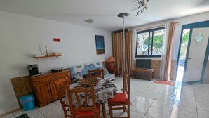 A dining area with a table set for four, a television, and a window with curtains. - Apartment Oasis Costa Calma (Costa Calma)