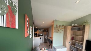 A modern living room with a sofa, a TV, and a wooden shelving unit. - Studio apartment on the first floor with outdoor area and parking space (Merlimont)
