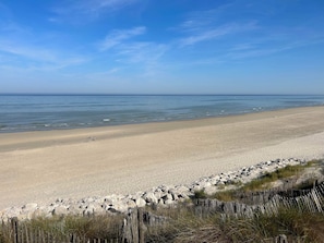 A beach with a wooden fence and rocks in the foreground, a sandy beach, and calm water. - Studio apartment on the first floor with outdoor area and parking space (Merlimont)